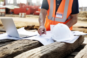 Worker in protective gear using a computer at a mine site, illustrating when to audit an MSHA Part 46 training program.