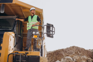 Man in PPE standing on heavy machinery at a surface mine